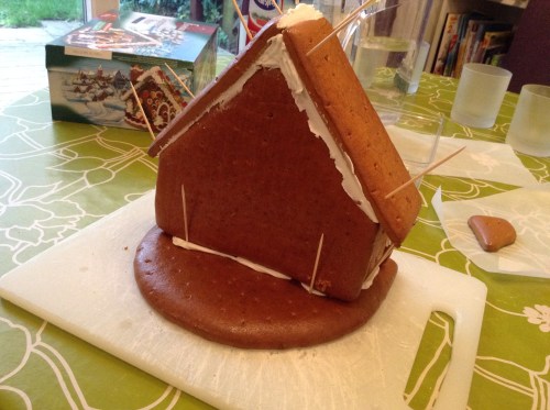 Putting the roof on. See all that white squishy stuff? That's royal icing. Never made that before; it was a real education. It's ready to use when it's got the consistency of cement, and it dries just as hard. Tastes better though!